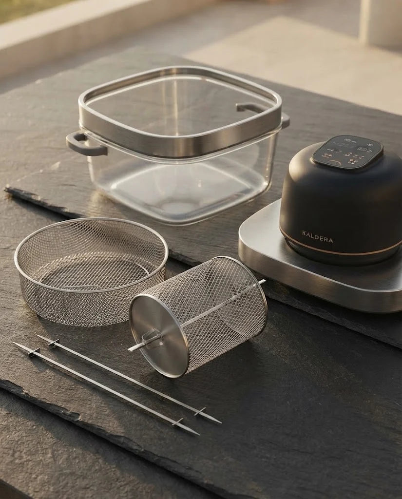 The stainless steel basket, rotisserie basket and skewers of Kaldera Glass laid out on a slate counter